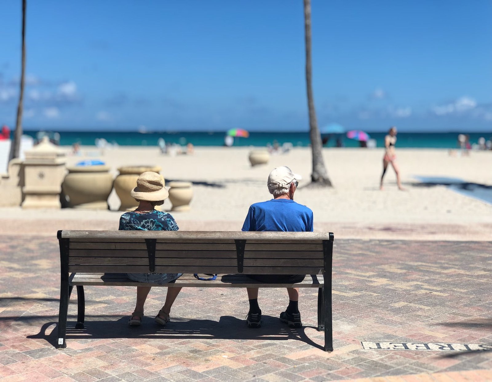 man and woman sitting on brown wooden bench